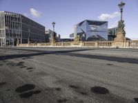 a city street with buildings and a bridge in the middle of it and the shadow of a man walking across a paved street from it