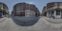 a 360 view lens of a cobbled down street and buildings in the middle of the day