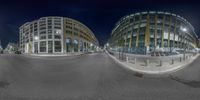 some buildings and a city street and buildings at night time with a fish - eye lens