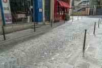 a street with some buildings next to a sidewalk with bars that line the side of it