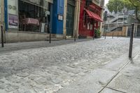 a street with some buildings next to a sidewalk with bars that line the side of it