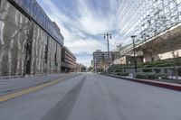 blurry photo of city street with buildings in background and empty road between curb and sidewalk