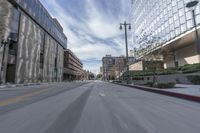 blurry photo of city street with buildings in background and empty road between curb and sidewalk