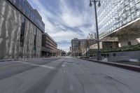 blurry photo of city street with buildings in background and empty road between curb and sidewalk