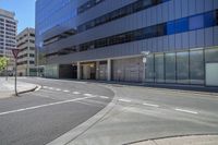 a curved road is in front of a glass building, with two empty street signs