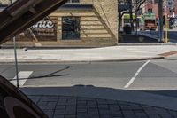 an empty city street with a car parked on the sidewalk and a traffic light in the foreground