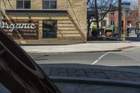 an empty city street with a car parked on the sidewalk and a traffic light in the foreground