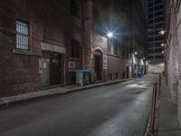 an empty city street with light post, sidewalk and building in the background at night