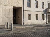 a person with a suitcase walking across an outside courtyard in front of a building,