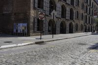 a street corner with a bricked curb, and cobblestone walkway with parking spaces on either side of it