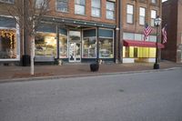 there is a small building on the street corner with shops on each side and american flags in the windows