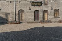 the person is walking down the street near old buildings on a sunny day with a red umbrella