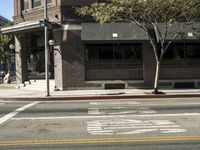 the fire hydrant is next to the street on the corner of the street that is painted black and has an awning