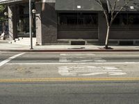 the fire hydrant is next to the street on the corner of the street that is painted black and has an awning