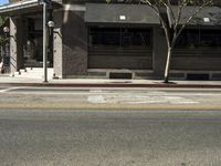 the fire hydrant is next to the street on the corner of the street that is painted black and has an awning