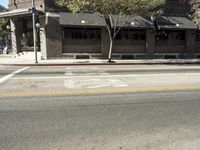 the fire hydrant is next to the street on the corner of the street that is painted black and has an awning