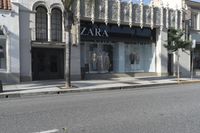 a street corner with an advertisement for the zara outlet on the wall and trees