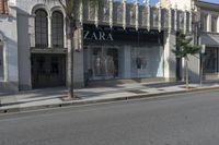 a street corner with an advertisement for the zara outlet on the wall and trees