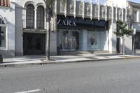 a street corner with an advertisement for the zara outlet on the wall and trees