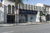 a street corner with an advertisement for the zara outlet on the wall and trees