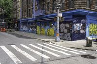 a white crosswalk on a city street near a building with graffiti painted on it