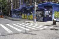 a white crosswalk on a city street near a building with graffiti painted on it