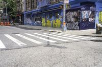 a white crosswalk on a city street near a building with graffiti painted on it