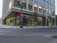 a city street in front of an empty building with buildings on one side and street lights