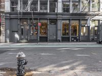 a city street with a fire hydrant on a sidewalk in front of a building