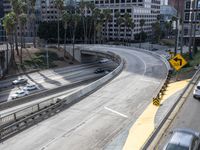 view of city street from freeway bridge in los angeles, california with cars driving underneath it