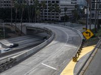 view of city street from freeway bridge in los angeles, california with cars driving underneath it