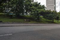 a city street with tall buildings and greenery behind it - the corner with street