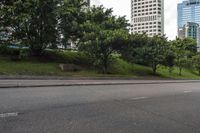 a city street with tall buildings and greenery behind it - the corner with street