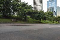 a city street with tall buildings and greenery behind it - the corner with street