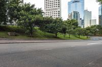 a city street with tall buildings and greenery behind it - the corner with street