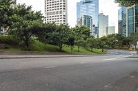 a city street with tall buildings and greenery behind it - the corner with street