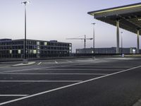 an empty car park with street lights on a blue dusk evening, with a parking lot in the foreground