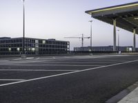 an empty car park with street lights on a blue dusk evening, with a parking lot in the foreground