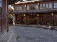 a street outside a large stone building with wooden doors and windows decorated with asian lanterns