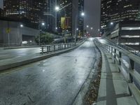 an empty street in the city is lined with tall buildings and lights on it's sides