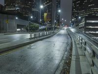 an empty street in the city is lined with tall buildings and lights on it's sides