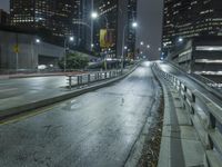 an empty street in the city is lined with tall buildings and lights on it's sides