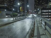 an empty street in the city is lined with tall buildings and lights on it's sides