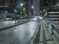 an empty street in the city is lined with tall buildings and lights on it's sides