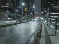 an empty street in the city is lined with tall buildings and lights on it's sides