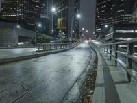 an empty street in the city is lined with tall buildings and lights on it's sides