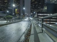 an empty street in the city is lined with tall buildings and lights on it's sides