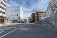 a city street with several tall buildings in the background, a man is driving on his motorcycle