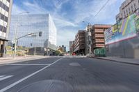 a city street with several tall buildings in the background, a man is driving on his motorcycle