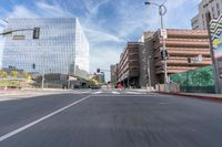 a city street with several tall buildings in the background, a man is driving on his motorcycle